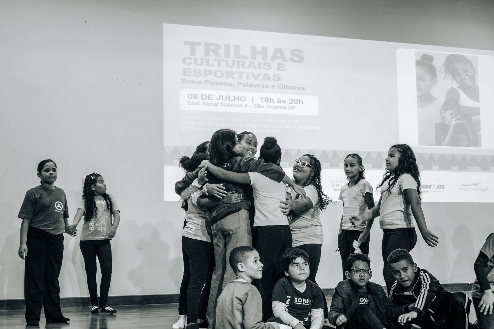 Grupo de adolescentes em abraço coletivo na Mostra Cultural do Instituto Alfa